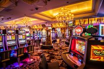 An electronic gaming machine lounge is set in golden tones. The area has a subtle feeling of luxury with its elaborate chandeliers and decorative ceilings.